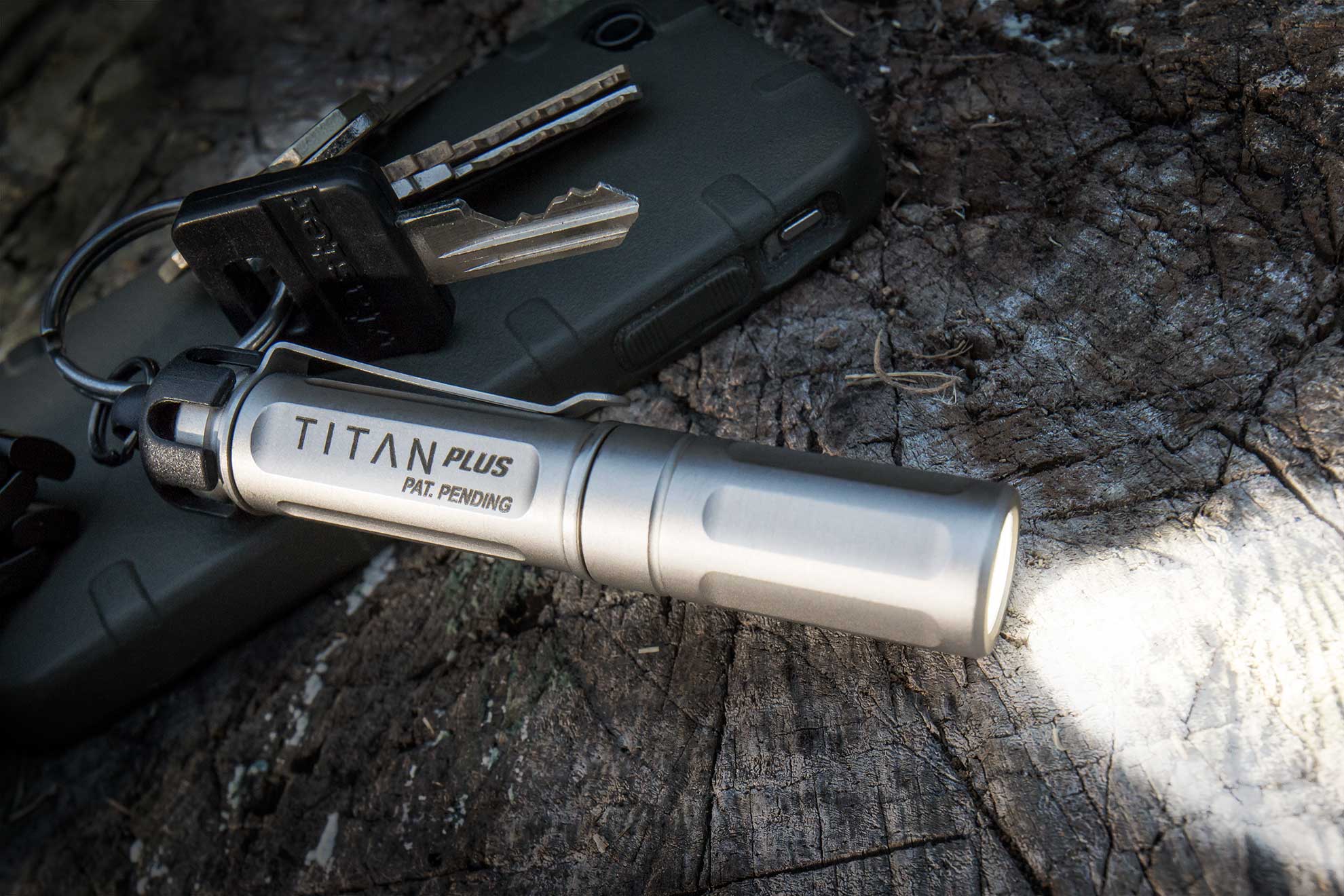 SureFire Titan Plus keychain flashlight with keys on log